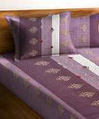 Purple bedspread with decorative patterns on a wooden bed frame.