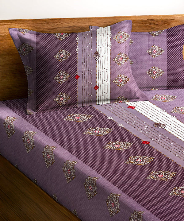 Purple bedspread with decorative patterns on a wooden bed frame.