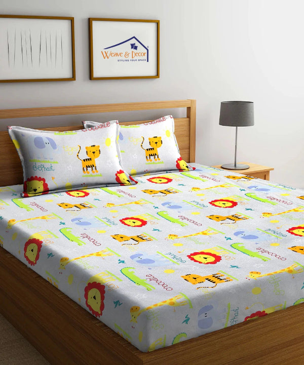 Children's bed with colorful bedding featuring animals and letters, with a lamp and framed pictures in the background.